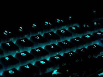 Close-up of a glowing gaming keyboard with blue backlighting in a dark ambiance.