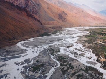 A breathtaking aerial view of river patterns cutting through Spiti Valley's mountainous terrain under a cloudy sky.