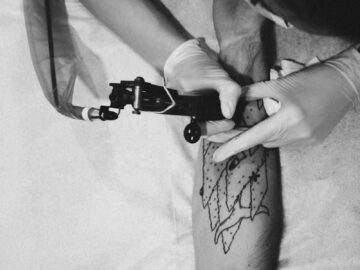 A tattoo artist skillfully designs a unique pattern on a client's arm in monochrome.