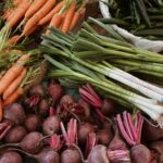 A variety of fresh vegetables including carrots, beetroots, and leeks on a market stall.