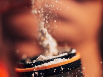 Dynamic shot of protein powder being added to a shaker, fitness concept.