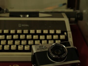 Close-up of a vintage camera and typewriter on a desk, creating a nostalgic vibe.