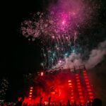 Energetic outdoor concert at night with a vibrant fireworks display and crowd enjoying live music.