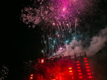 Energetic outdoor concert at night with a vibrant fireworks display and crowd enjoying live music.