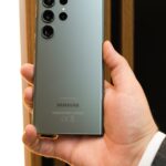 Close-up of a person holding a sleek Samsung smartphone with a triple camera setup.