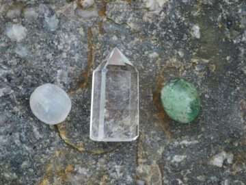 Assorted healing crystals including quartz on a textured stone surface.