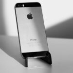 A sleek black and white close-up of an iPhone on a stand, highlighting minimalist design.