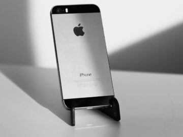 A sleek black and white close-up of an iPhone on a stand, highlighting minimalist design.
