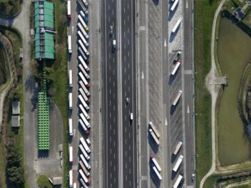 Highway traffic captured from above showcasing trucks and parked vehicles in Roncade, Italy.