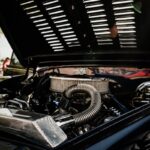 Detailed view of vintage car engine with open hood on a sunny day.