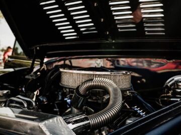Detailed view of vintage car engine with open hood on a sunny day.