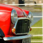 Close-up of a vintage red Mini car against a city backdrop.
