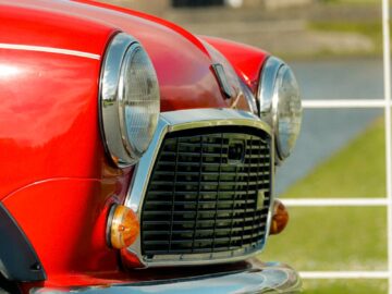 Close-up of a vintage red Mini car against a city backdrop.