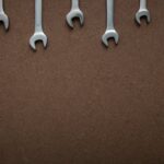 Flat lay of several wrenches lined up on a brown textured background with copy space.