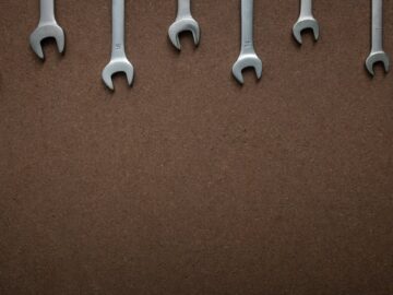 Flat lay of several wrenches lined up on a brown textured background with copy space.