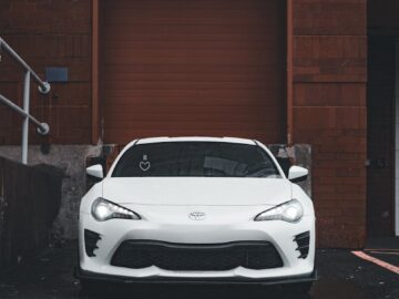 A white sports car parked in a rainy urban area, emphasizing its sleek design.