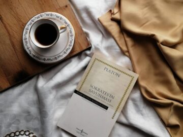 An aesthetically pleasing still life featuring a coffee cup, book, and draped fabric.