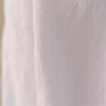 A detailed view of crumpled white linen fabric creating an abstract and minimalistic background.