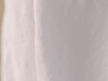 A detailed view of crumpled white linen fabric creating an abstract and minimalistic background.