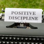 A vintage typewriter outdoors with paper showing 'Positive Discipline'.