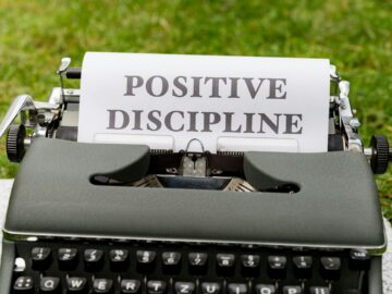 A vintage typewriter outdoors with paper showing 'Positive Discipline'.