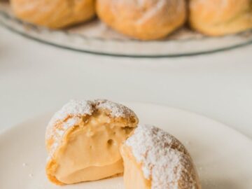 Close-up of cream-filled pastries dusted with powdered sugar on a white plate.