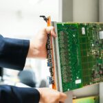 A technician inserts a circuit board into a server rack, illustrating technology and connectivity.