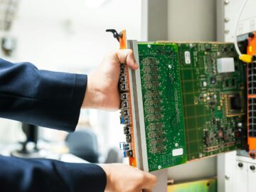 A technician inserts a circuit board into a server rack, illustrating technology and connectivity.