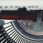 Close-up of a vintage typewriter typing 'giving up is not an option.'