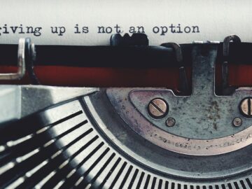Close-up of a vintage typewriter typing 'giving up is not an option.'