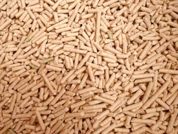 A detailed top view of a large pile of wood pellets used for renewable fuel and energy.