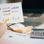 Close-up of hands analyzing financial data with charts, laptop, and calculator.