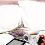 Relaxing breakfast in bed with tea, fruit, lavender, and a tablet for a peaceful morning.