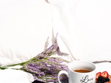 Relaxing breakfast in bed with tea, fruit, lavender, and a tablet for a peaceful morning.