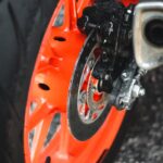 Detailed view of an orange motorcycle wheel with a visible brake disc.