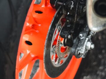 Detailed view of an orange motorcycle wheel with a visible brake disc.