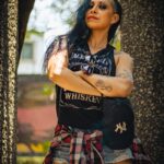 Portrait of a tattooed woman in a park, showcasing her alternative fashion and confident stance.