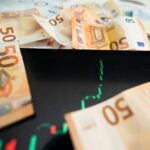 Close-up of 50 euro banknotes with a digital stock market chart on a tablet, depicting financial growth.