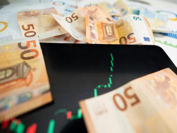 Close-up of 50 euro banknotes with a digital stock market chart on a tablet, depicting financial growth.