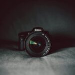 A camera lens in focus against a dark background, highlighting the optical details.