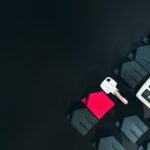 Real estate concept image featuring a calculator, houses, and a key on a black background.