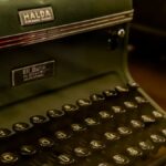 Close-up of a vintage Halda typewriter with a dark green finish, showcasing nostalgic charm.
