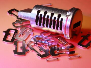 Detailed image of a disassembled lock cylinder and its metal components on a colored surface.