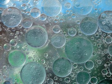 Close-up macro photo of oil bubbles on a water surface creating an abstract pattern.