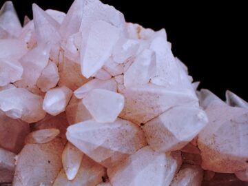 Stunning close-up of pink quartz crystals with detailed facets against a dark background.
