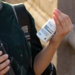 Close-up of person holding a hair supplement bottle outdoors, Los Angeles.