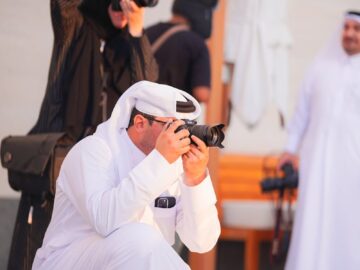 Group of photographers in Doha capturing cityscapes, embracing cultural attire and modern technology.