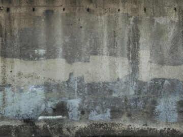 A close-up of a textured concrete wall showcasing painted layers in Avila Beach, CA.