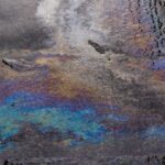Rainbow-like oil spill pattern on wet asphalt creates vivid color display.
