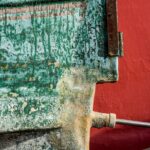 Detailed close-up of a rusty metal object against a vibrant red background.